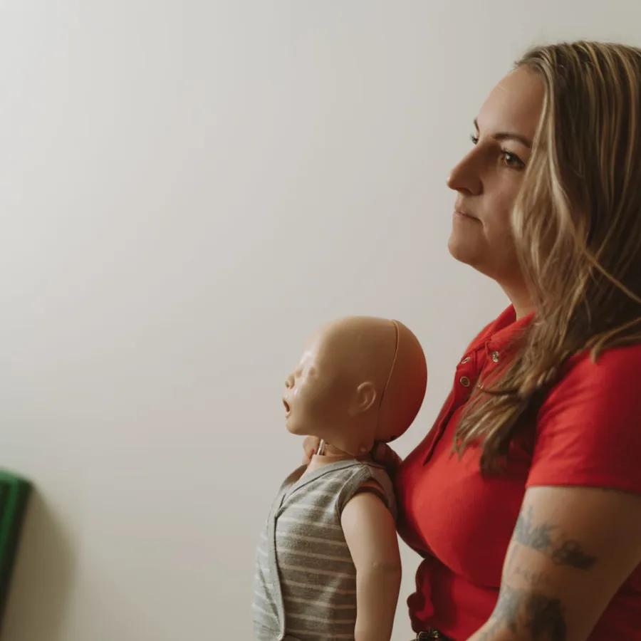 Une formatrice Famille de Sauveteurs avec un mannequin nourrisson pendant une formation à domicile